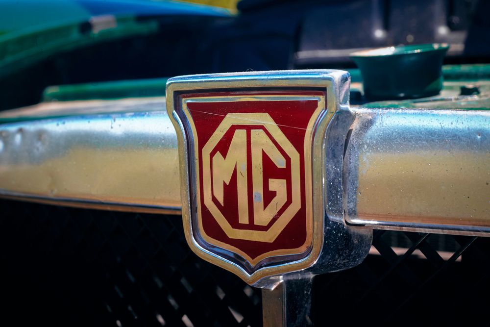 Series of vintage MG emblems and badges showing classic British car branding.