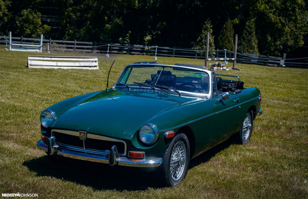 Multiple angles of a green classic MG convertible parked on grass with white fence background.