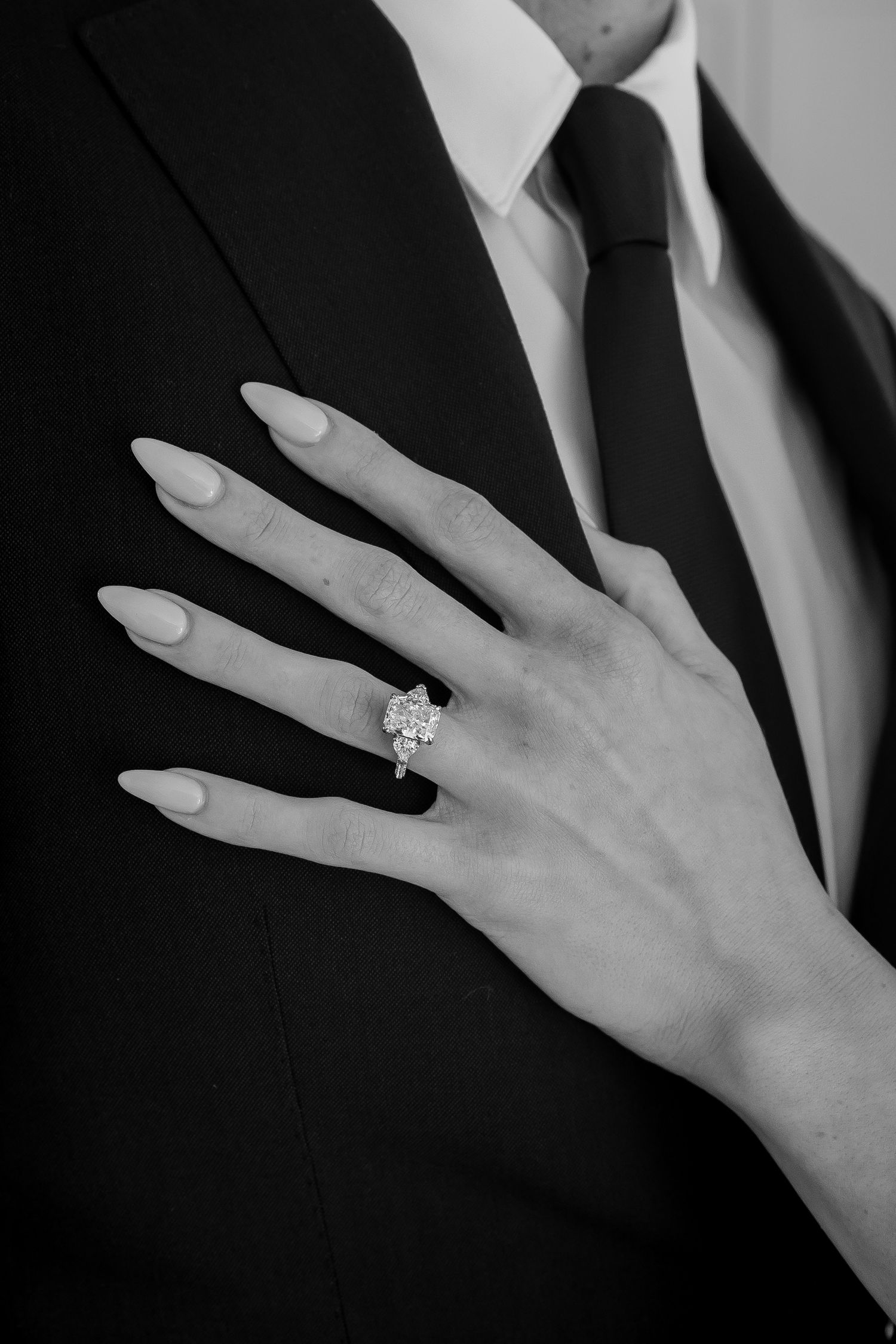Close-up black and white photos of a sparkling engagement ring on a hand against formal wear.