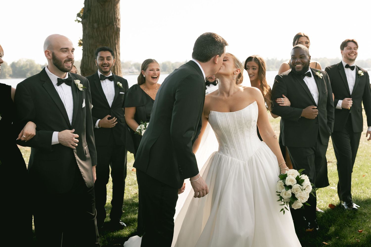 Wedding party gathered outdoors for formal photographs in elegant attire.