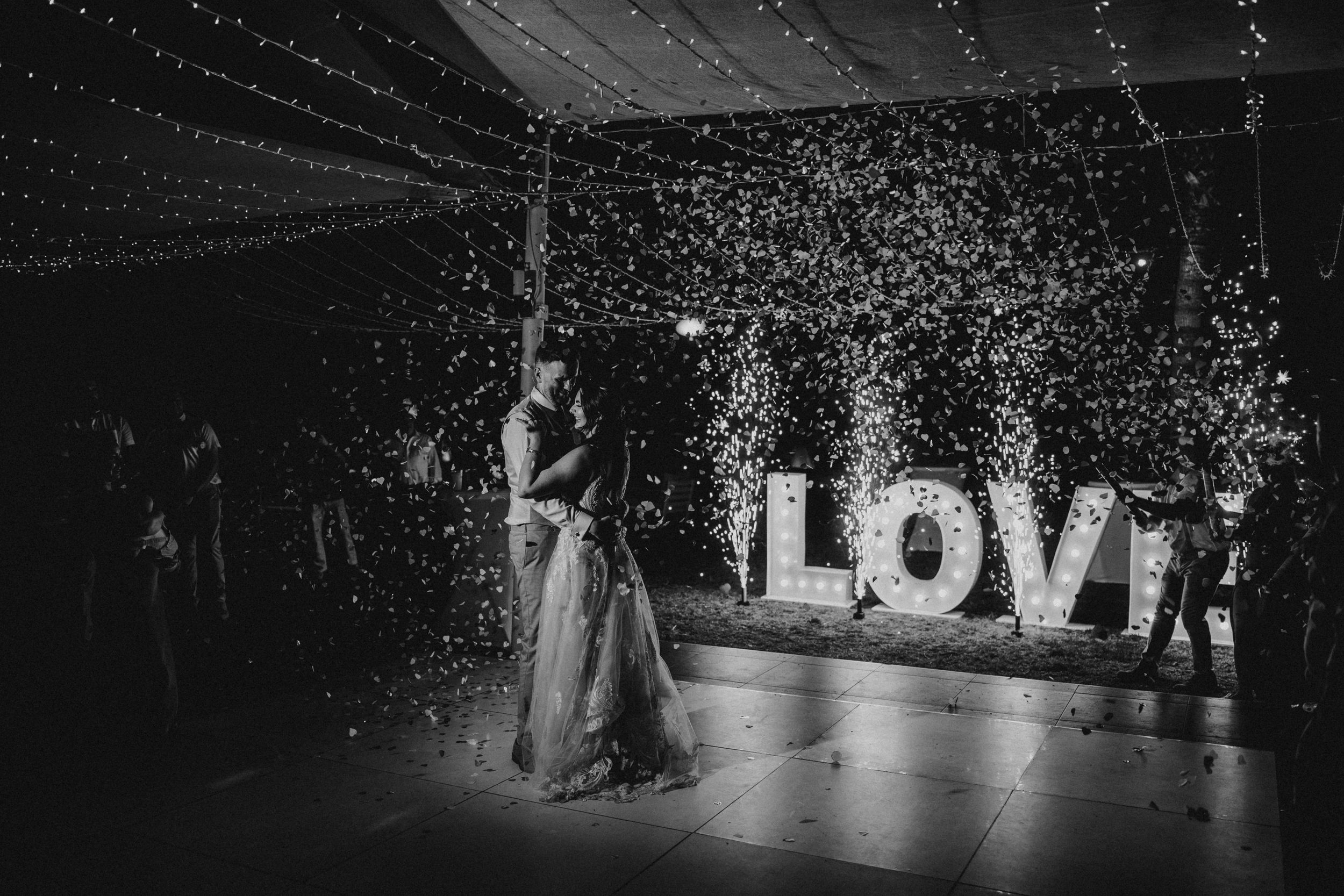 Wedding dance floor with illuminated LOVE sign and string lights creating romantic atmosphere.