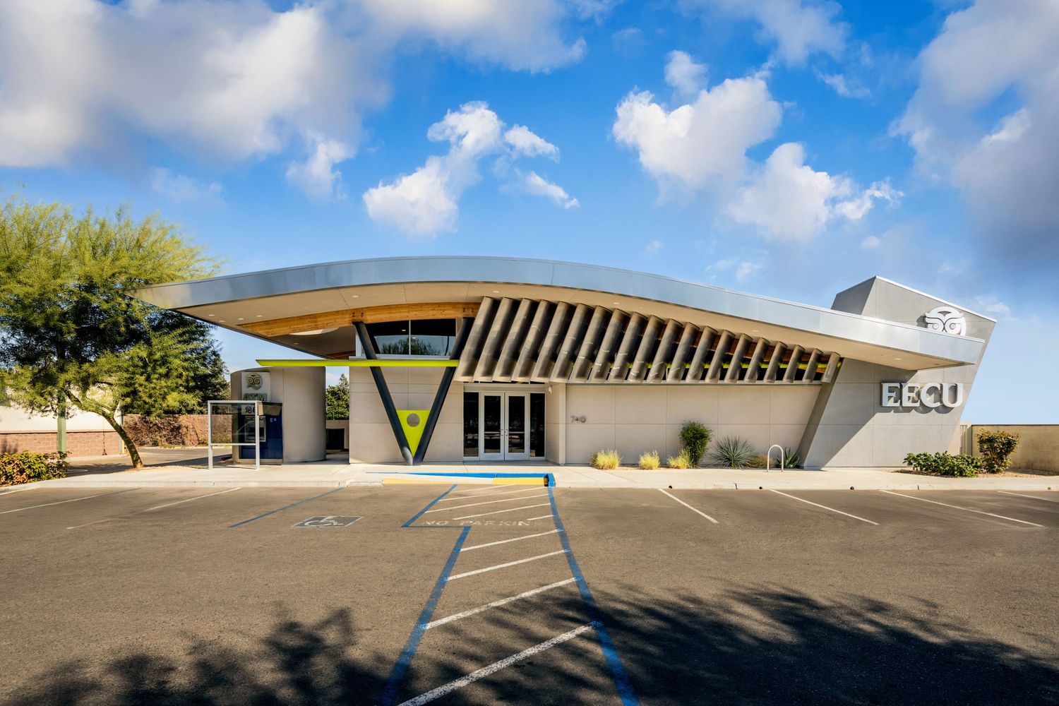 Modern angular mid-century building with distinctive sloped roof under blue sky.