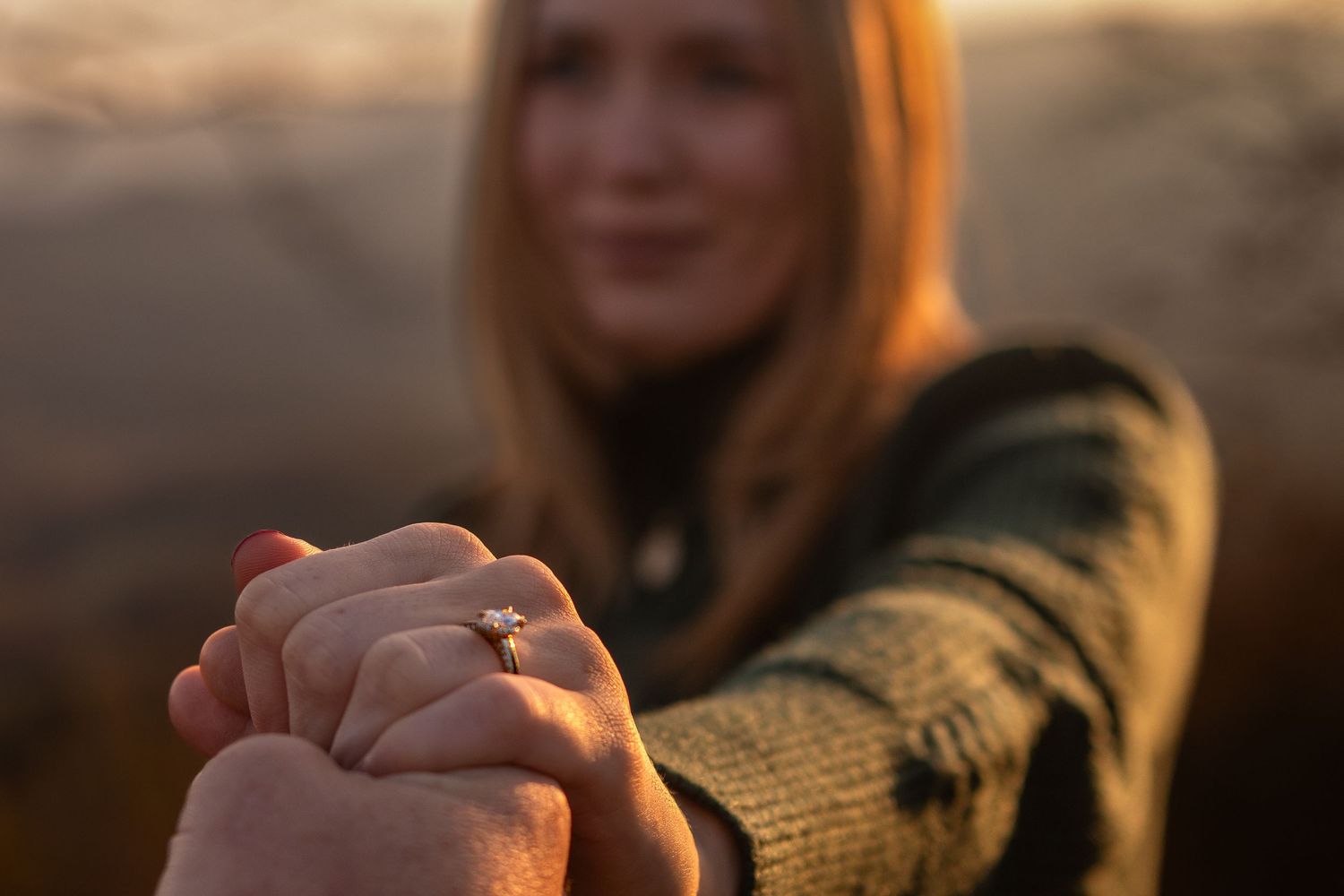 A romantic outdoor portrait showing hands with an engagement ring adorned with yellow flowers.