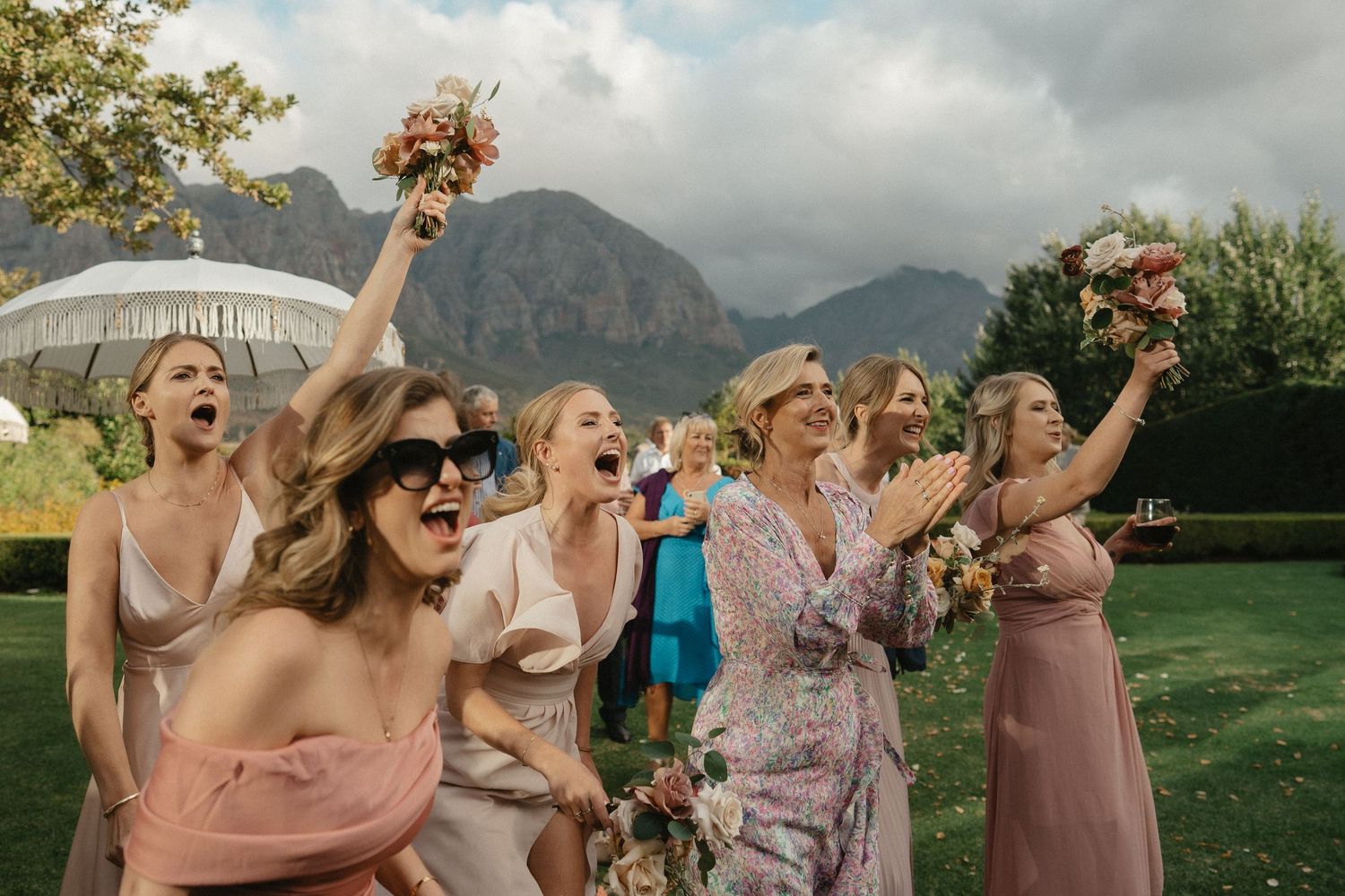 Intimate mountaintop wedding ceremony with guests gathered on a scenic overlook above a coastal landscape.