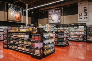 Grocery store aisle with colorful product displays and red floors showing beverage section.
