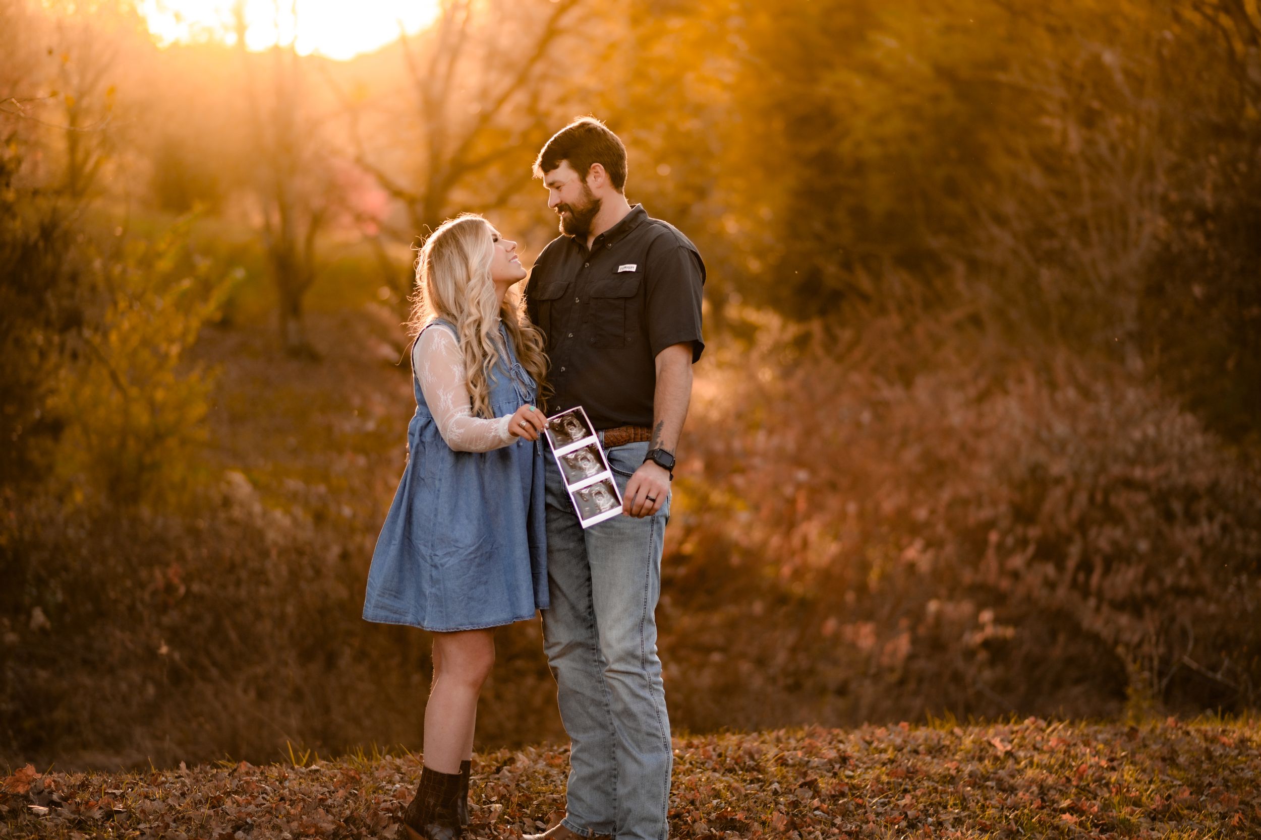 Romantic couple sharing a tender moment at sunset in an autumn field.