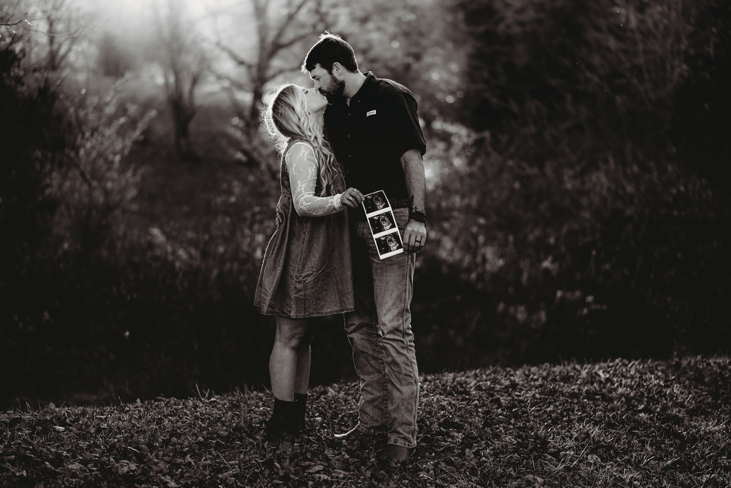 Black and white portrait of a couple standing close together in a misty outdoor setting.