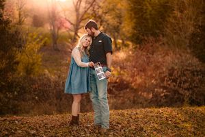 Couple embracing during golden hour with autumn foliage in the background.