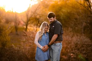 Couple sharing an intimate moment during sunset with golden light filtering through trees.