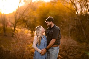 Couple embracing in warm sunset light with autumn colors surrounding them.