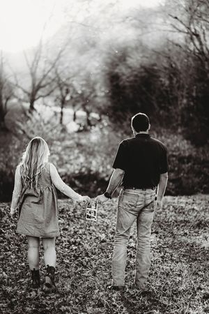 Black and white silhouette of a couple walking through a misty field.