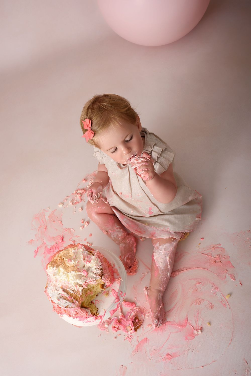 Overhead view of cake smash photo session with pink frosting scattered on floor.