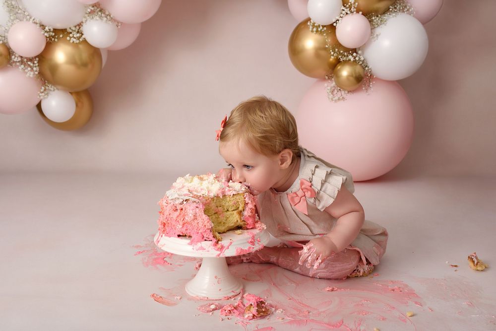 Pink and gold themed cake smash photography session with messy frosting.