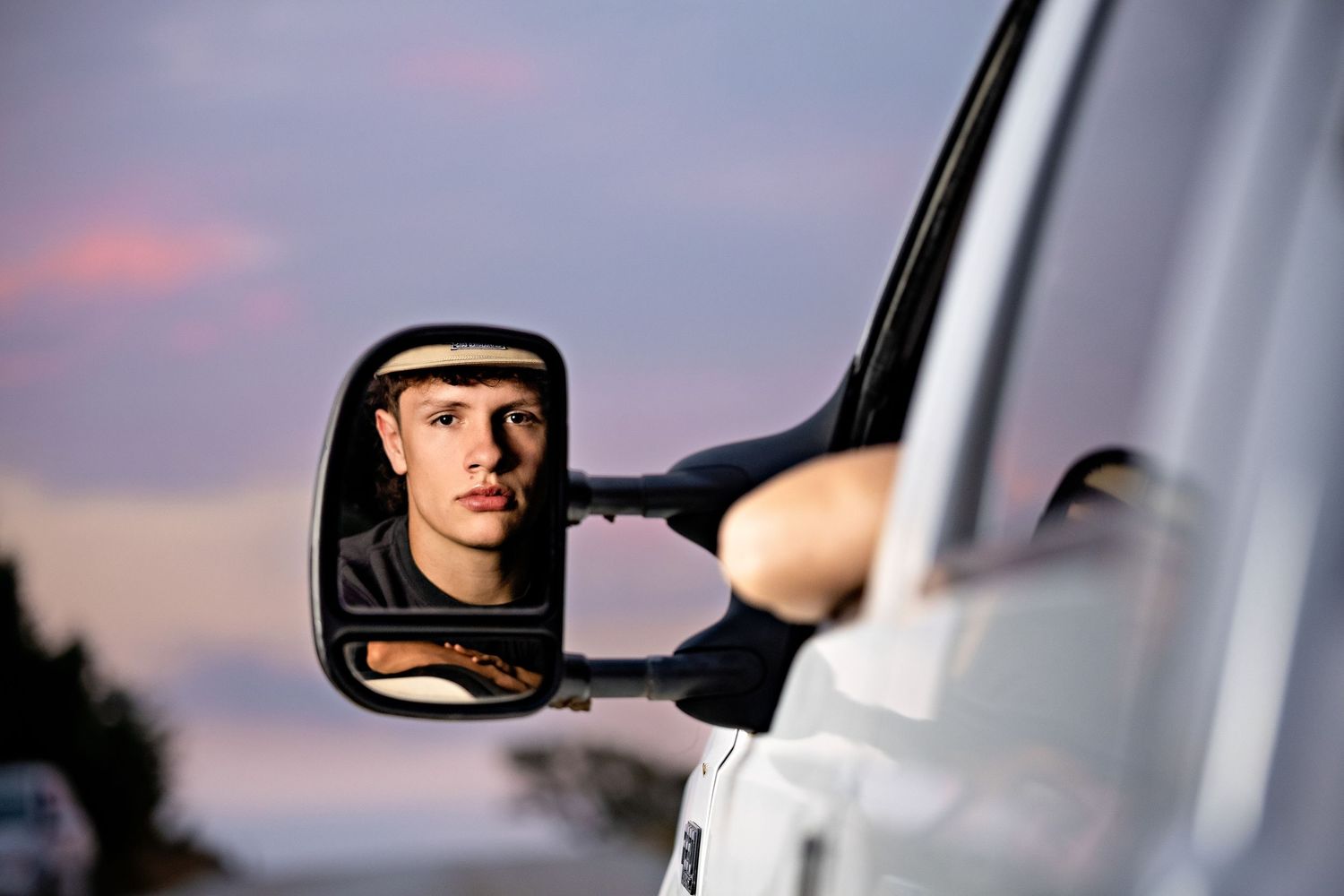 A sequence of mirror reflections showing someone adjusting a motorcycle rearview mirror at sunset.