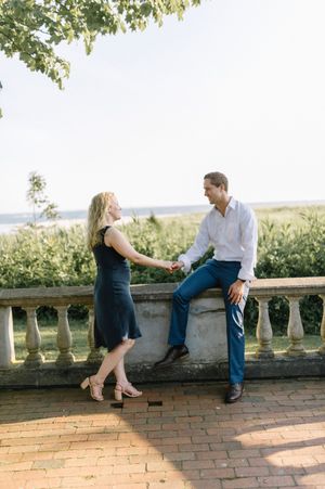 Couple shares a romantic moment on a brick terrace overlooking a scenic landscape on a sunny afternoon.