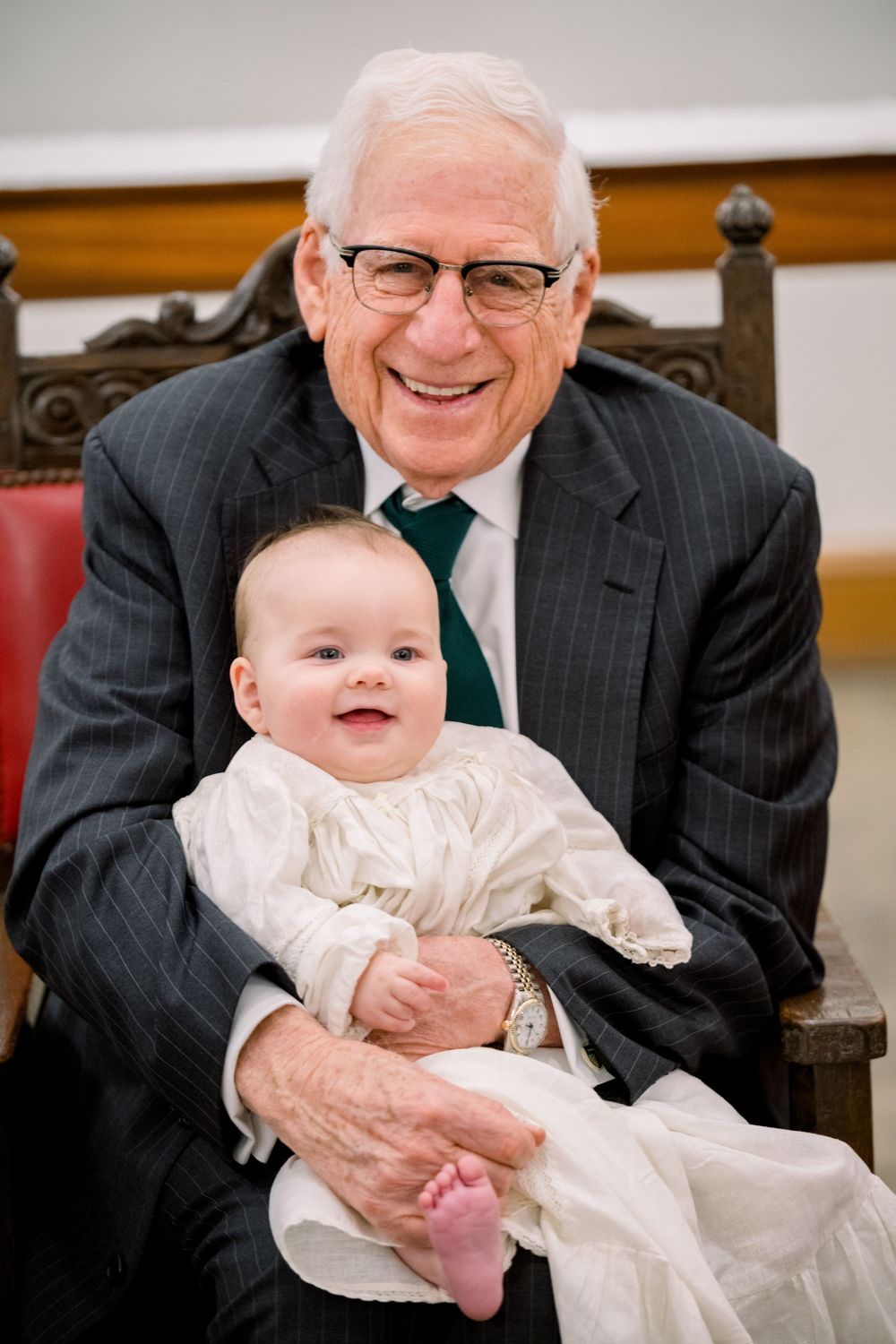 A series of heartwarming moments between a baby in white christening gown and elderly relative indoors.