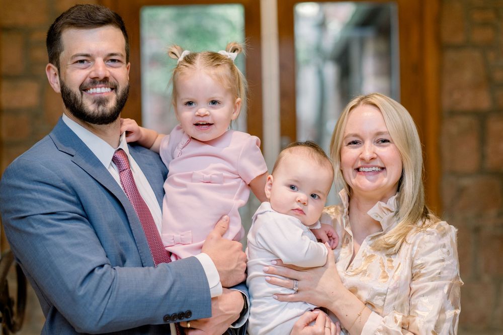 A happy family poses together in front of a rustic brick wall background during a photo session.
