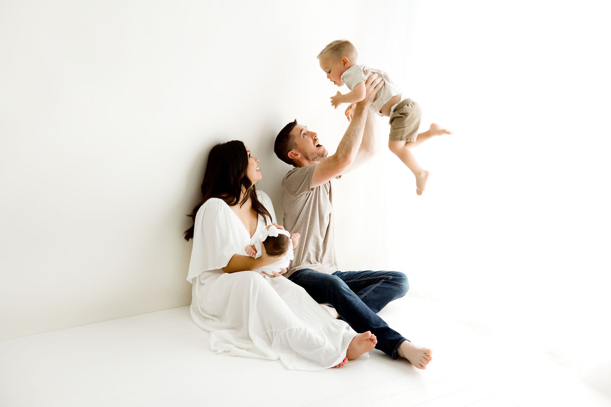 Candid newborn photograph with mom holding a newborn baby girl and dad playing with their older son. Chicago newborn session.
