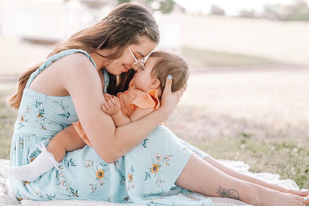 Family members sharing affectionate moments outdoors in soft lighting.