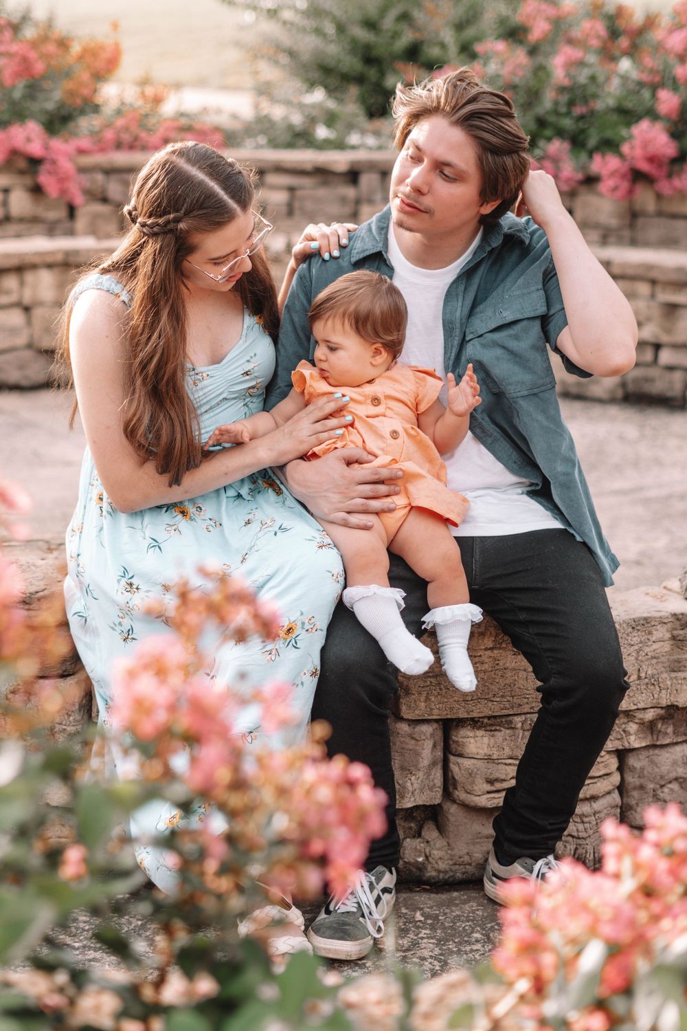 Family portrait session among blooming pink flowers and stone walls.