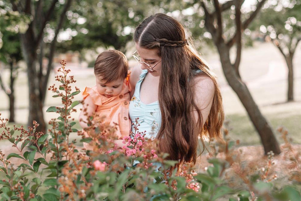 Family portrait session in garden setting with blooming pink flowers.