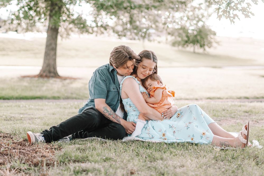 Relaxed outdoor family photography session in a sun-dappled park setting.