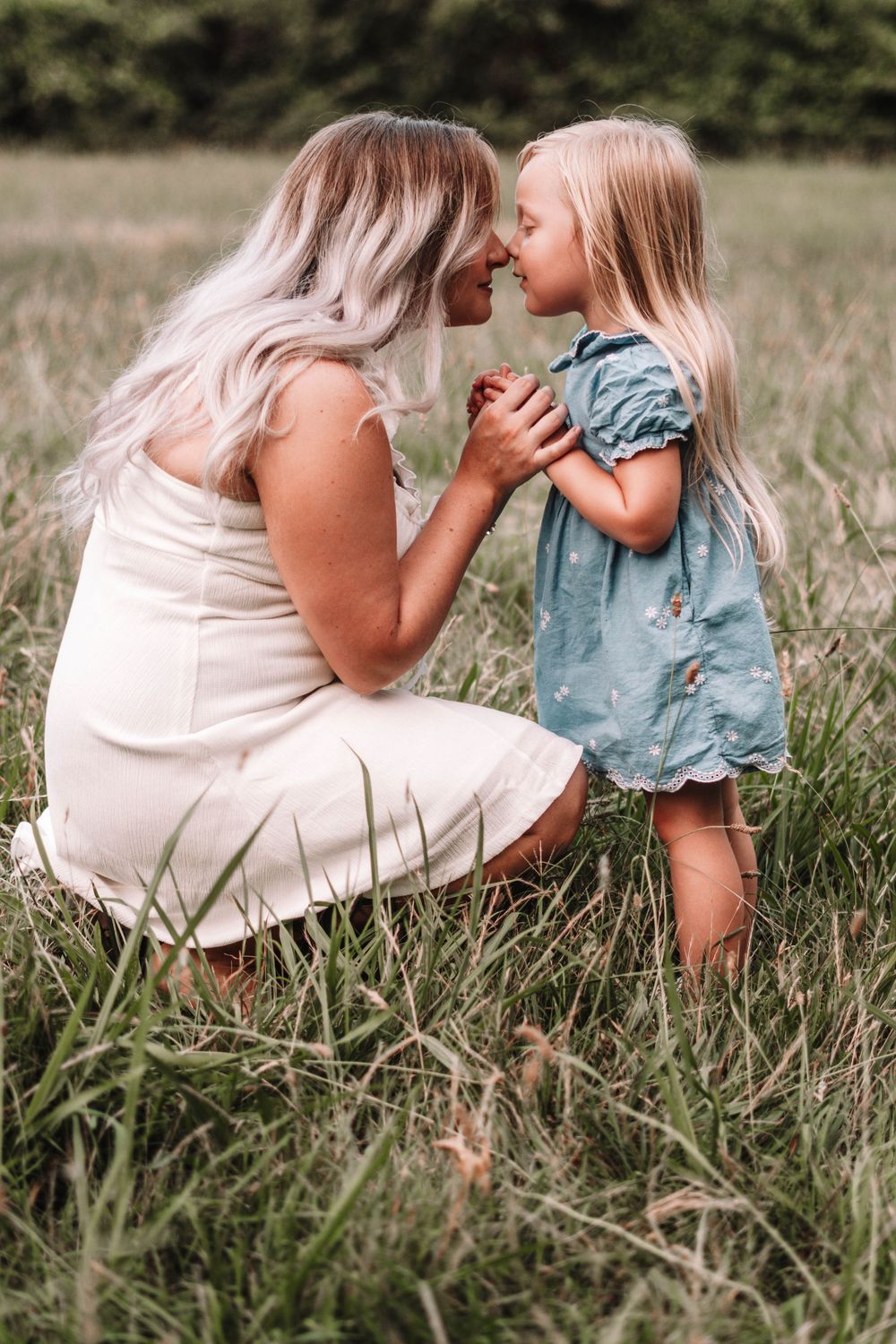 Intimate outdoor photography session in tall grass with soft natural lighting.