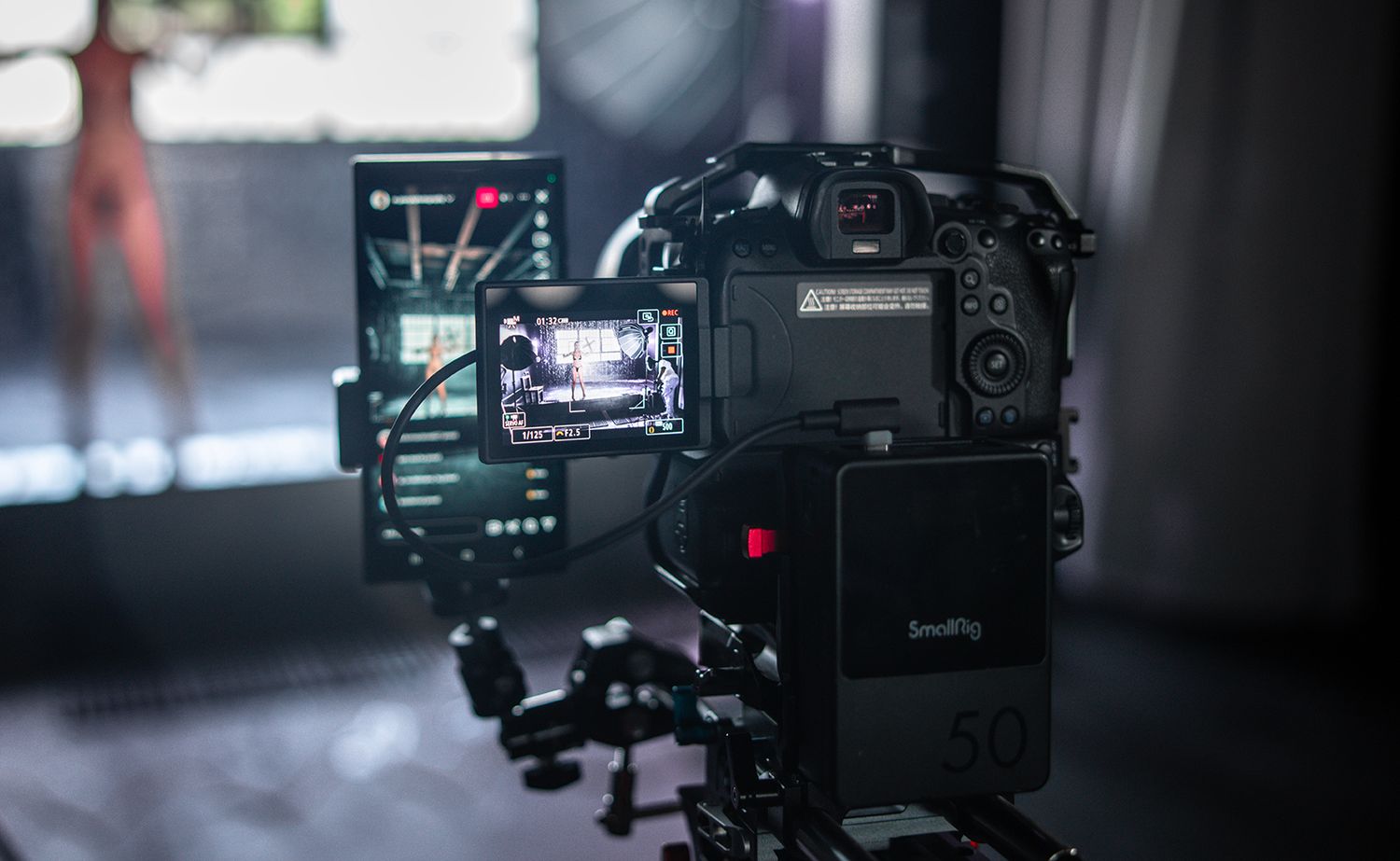Professional video camera setup with LCD display screen in a dim studio environment.
