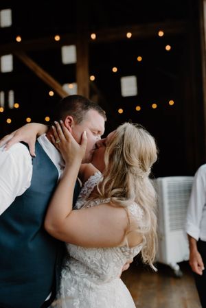 Romantic moment captured during wedding reception with twinkle lights in background.
