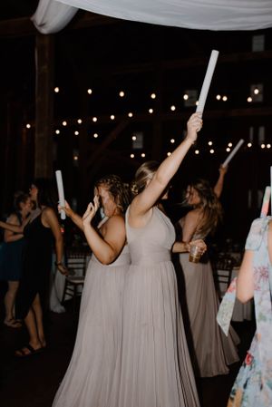 Bridesmaids in flowing dresses dance with light-up batons at reception.