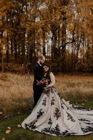 A stunning black and white wedding gown with lace details photographed in a fall setting.