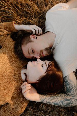 Couple laying on autumn blanket sharing intimate moment during outdoor photoshoot.
