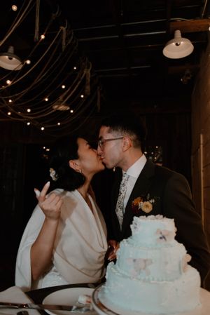 A wedding reception moment with a three-tiered white cake under romantic string lights.