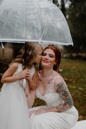 Sweet moment shared under clear umbrella during outdoor wedding portraits.