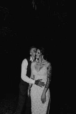 A romantic black and white portrait of a couple embracing in formal attire at night.