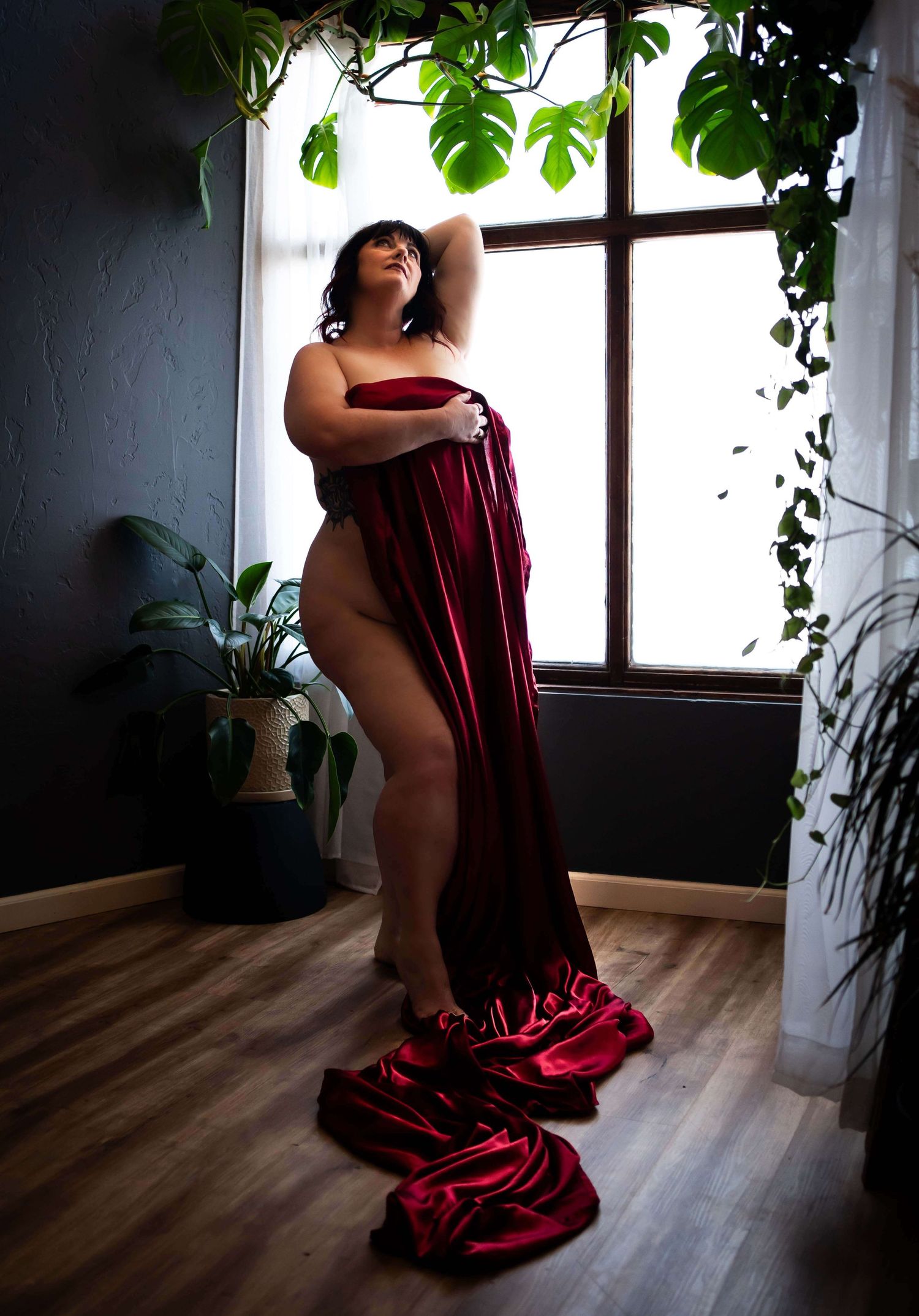woman standing holding a red sheet in front of her