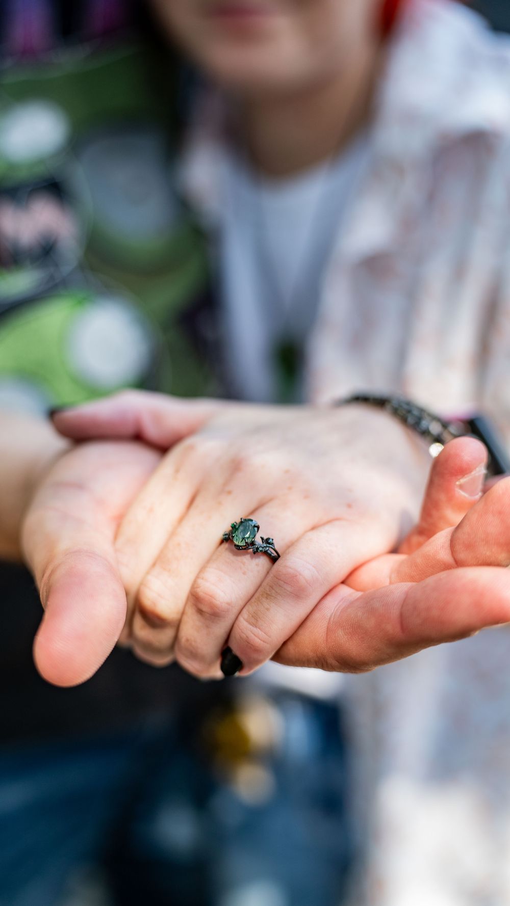 Close-up sequence showing an engagement ring with a teal stone being held against a blurred outdoor background.
