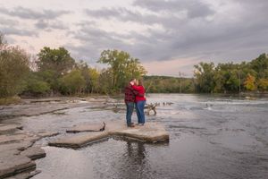 Scenic view of a rocky river with cascading water and cloudy skies during autumn season.