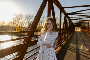 Sun flare photo on rustic bridge with white dress in golden light.