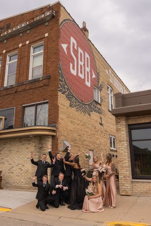 Wedding party in formal attire poses playfully outside a brick building entrance in progressive sequence photos.