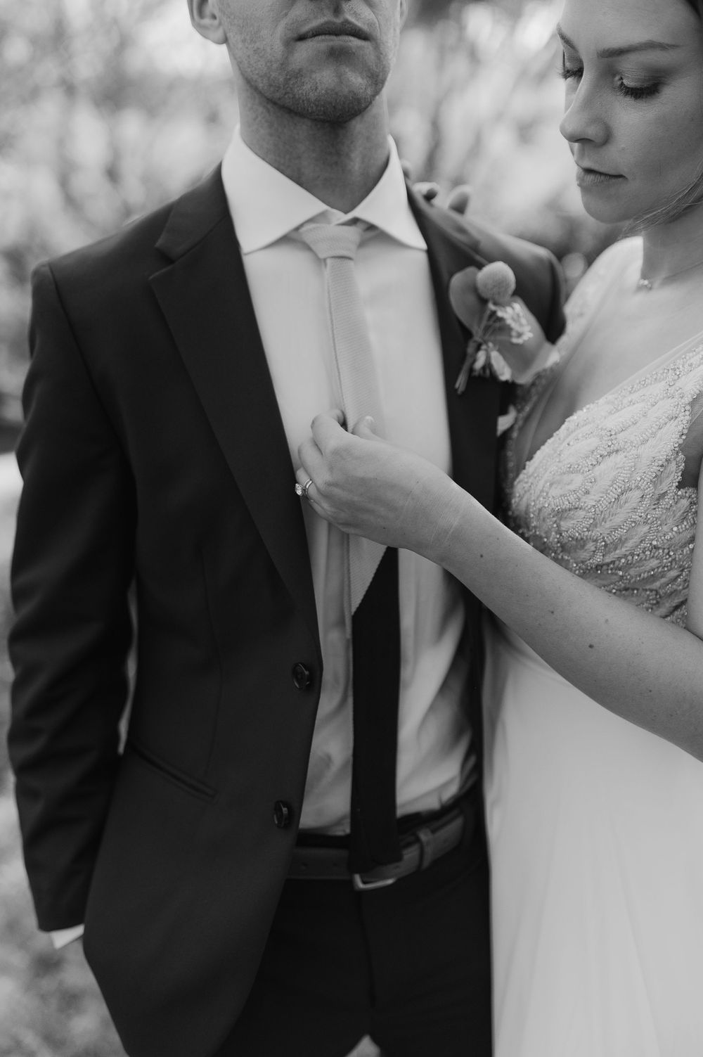 Intimate black and white portrait showing wedding attire details and boutonniere.