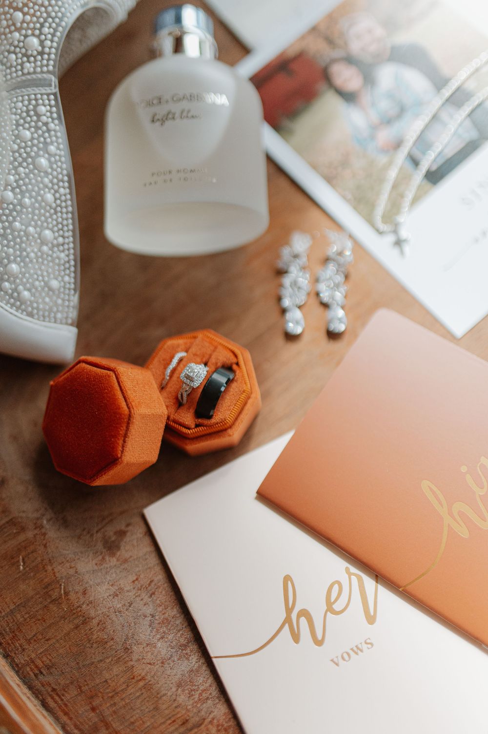 Wedding accessories including perfume, jewelry box and invitation on wooden surface.