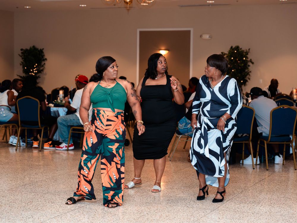 Three women dancing in colorful outfits at an indoor event space.