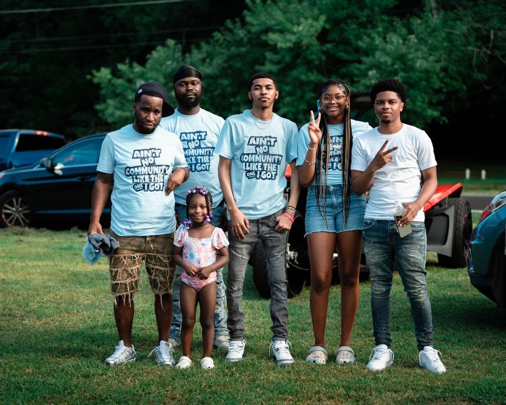 A group poses outdoors wearing matching t-shirts and casual attire.