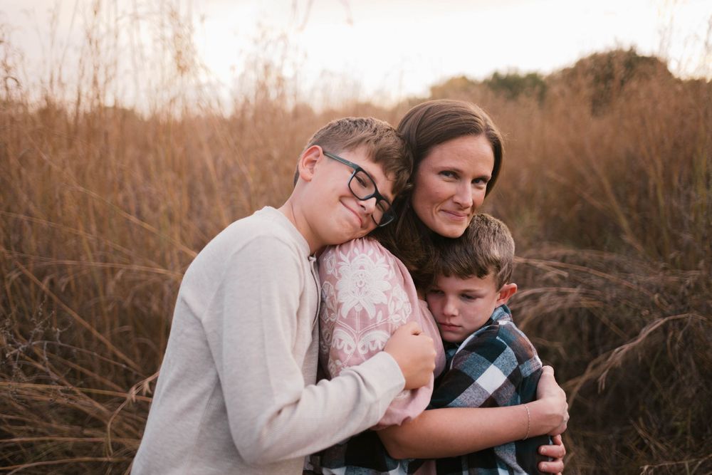 Authentic lifestyle portrait of a mother and her two sons sharing a warm embrace in a natural outdoor setting
