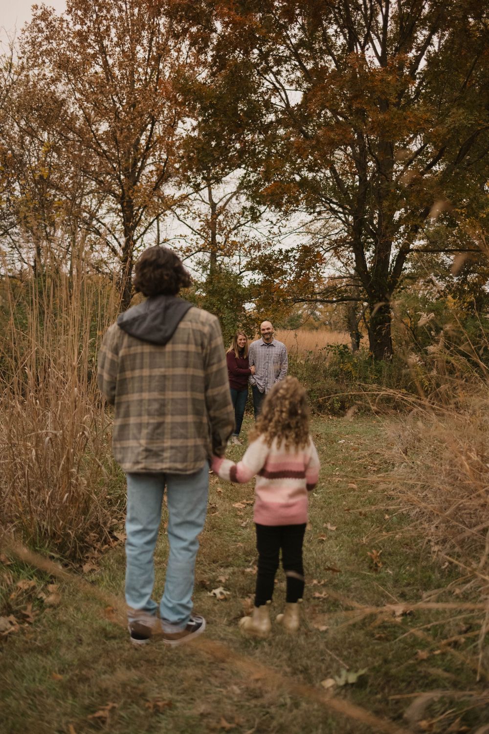 A candid portrait of a big brother and little sister looking down at their parents while smiling.