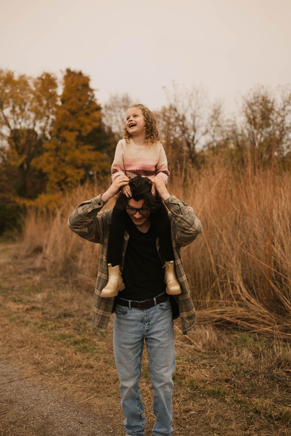 Candid portrait of a big brother and little sister laughing and playing together during an outdoor photography session