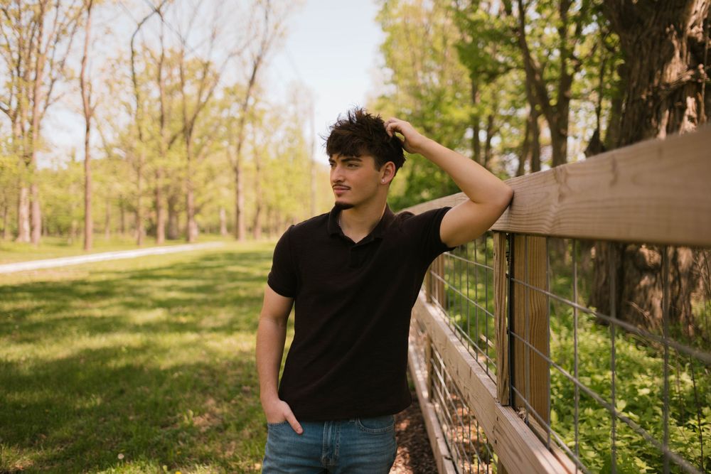 Portrait of a senior boy posing against a wooden fence at Lincoln Memorial Gardens in Illinois.
