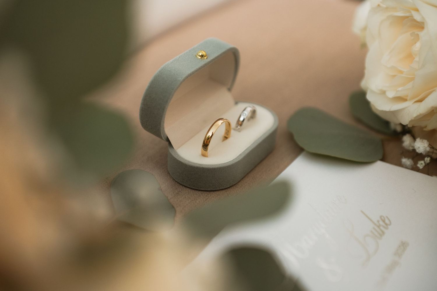 Wedding rings displayed on elegant paper with delicate floral details.