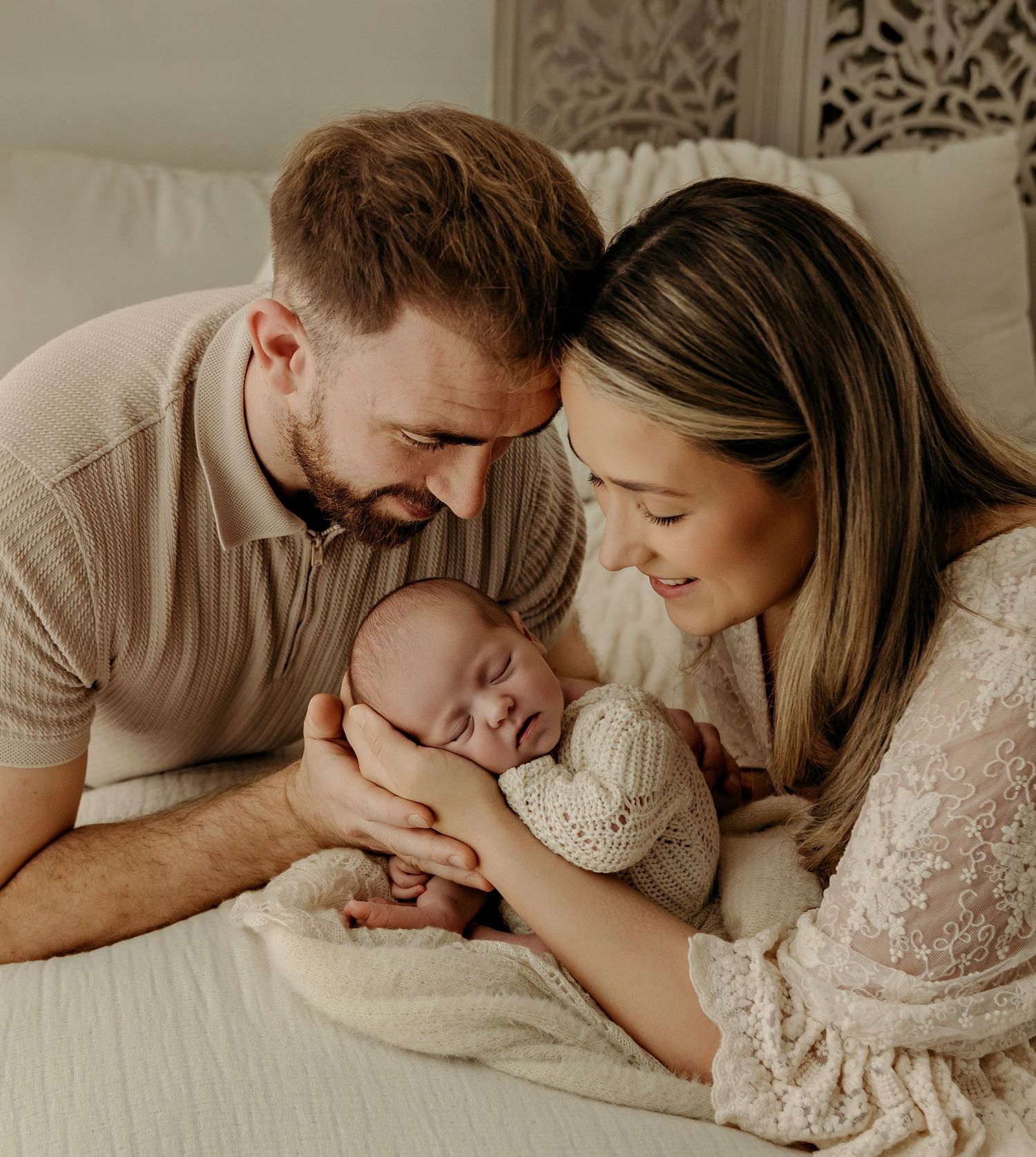 Natural Newborn Photographer Westmeath. New mum and dad dressed in cream and beige craddling their newborn daughter in their hands